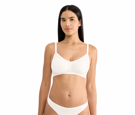 Žena v bílé žebrované měkké podprsence sloggi ZERO Feel Pure Soft bra a ladících kalhotkách, dívá se dopředu.