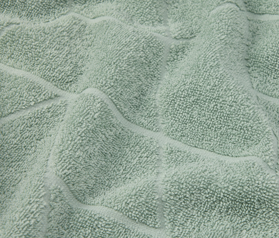 Detailní záběr světle zeleného texturovaného ručníku.