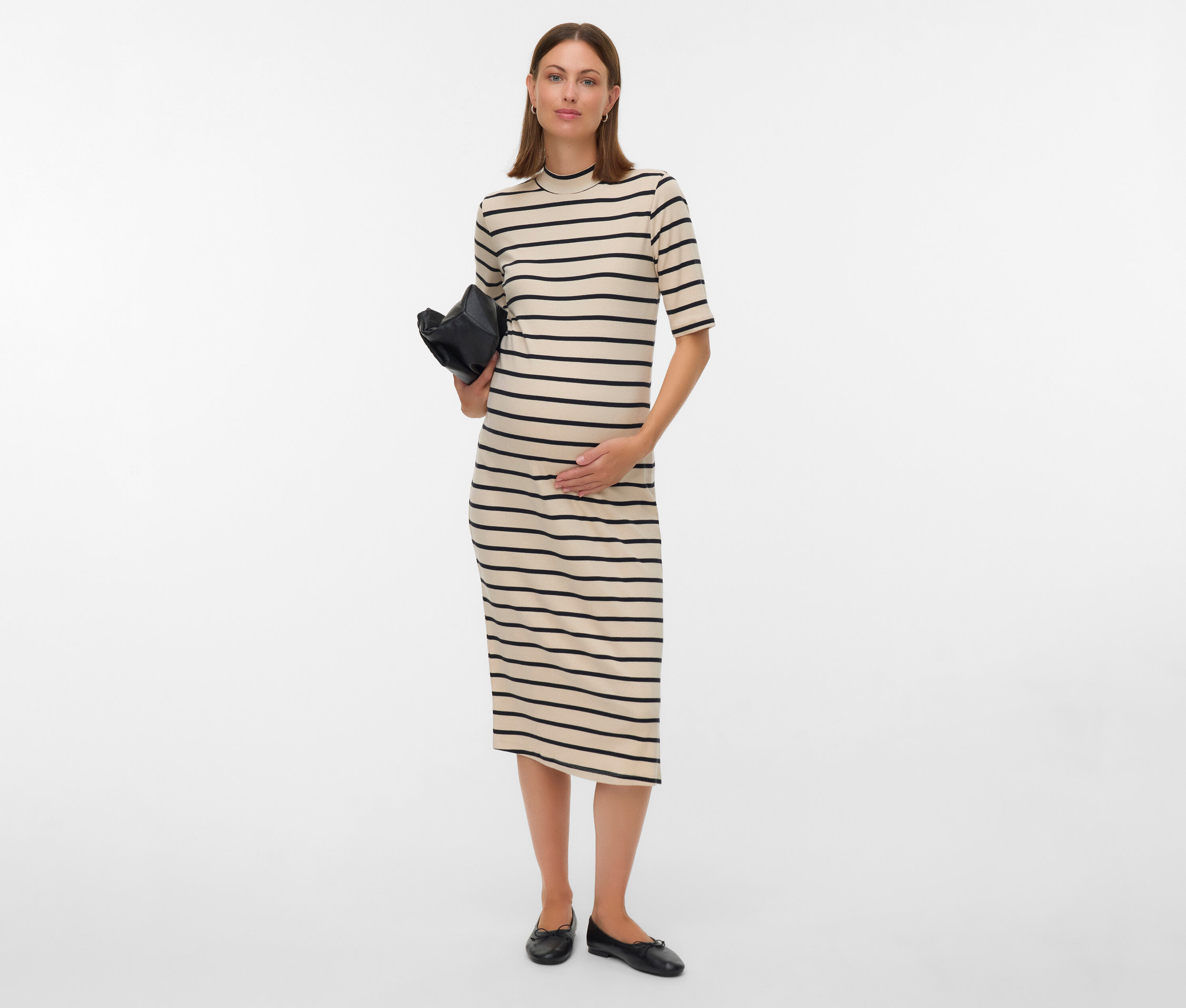 Těhotná žena v pruhovaných šatech drží černou kabelku.
