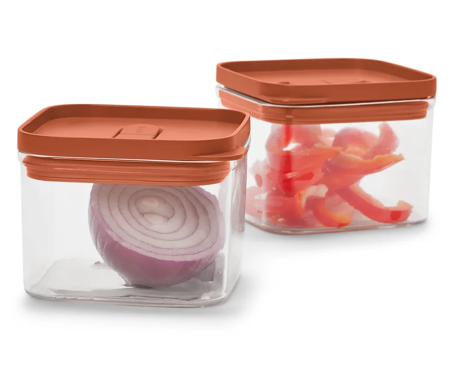 Dvě průhledné čtvercové nádoby s oranžovými víčky. V jedné je červená cibule, v druhé nakrájená červená paprika.