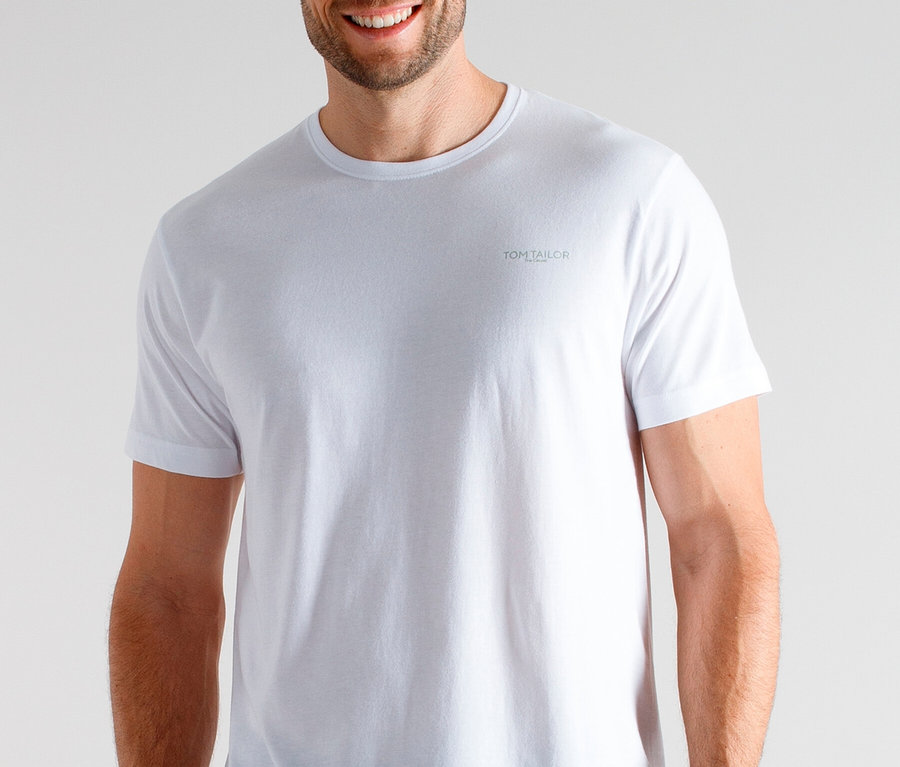 Usmívající se muž má na sobě bílé tričko a kostkované pyžamové kalhoty.