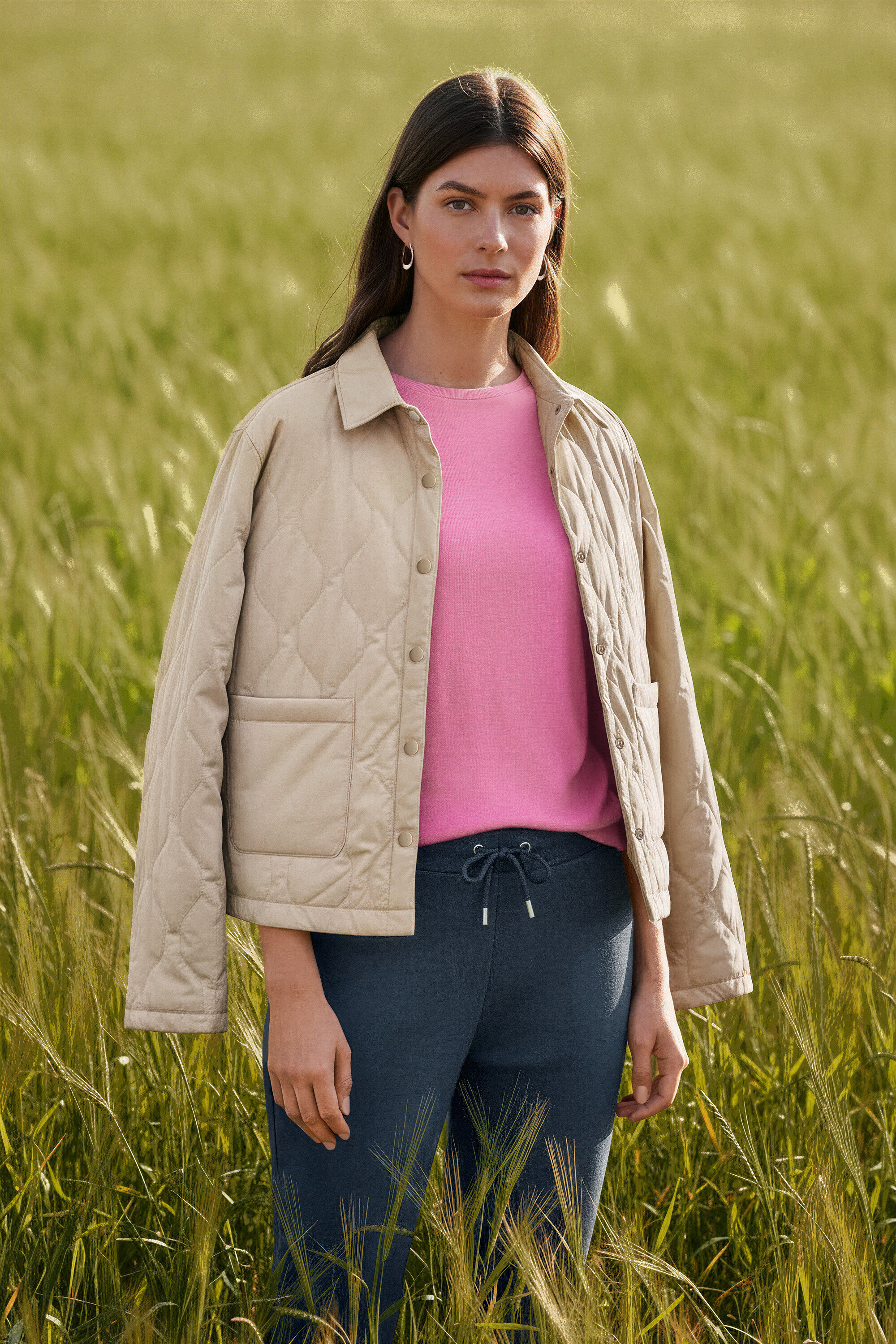 Žena stojí v poli a má náušnice Wave.