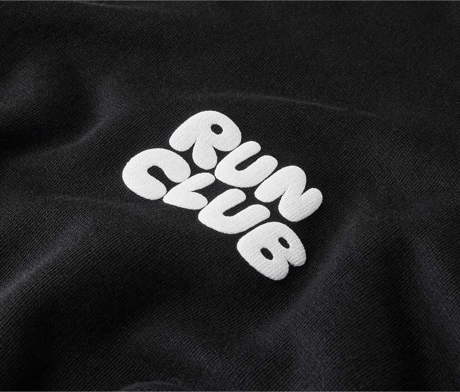 Detail černé mikiny s bílou výšivkou „RUN CLUB“.