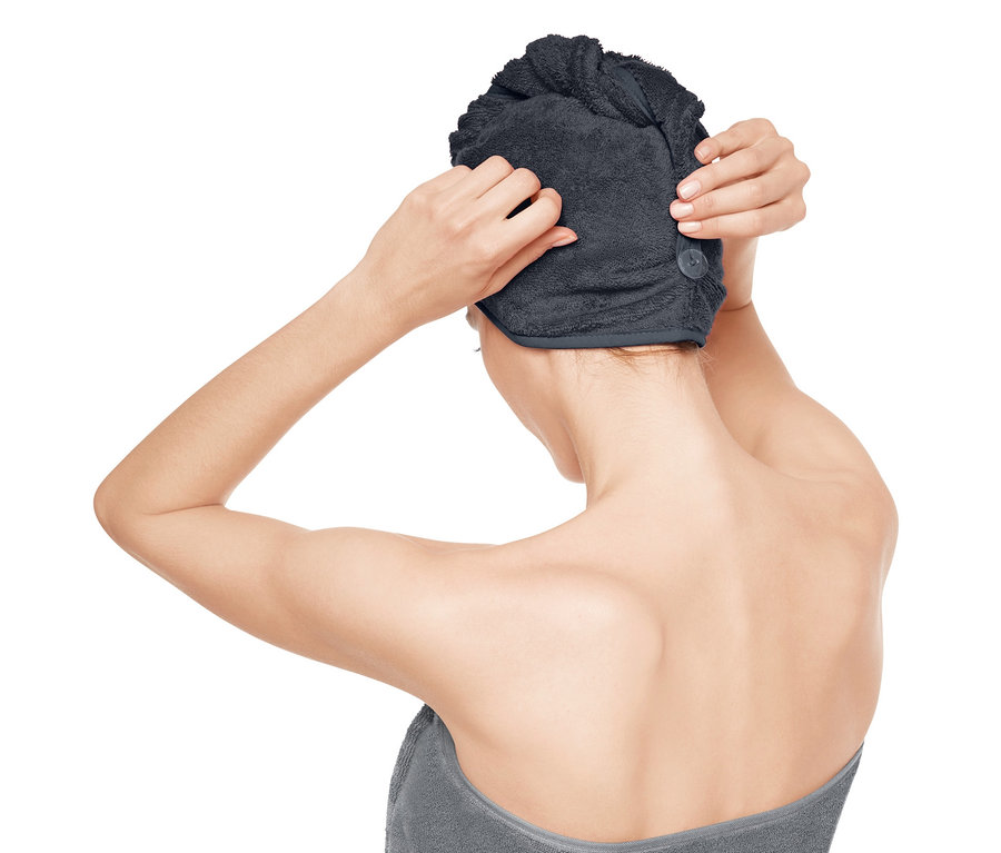 Žena si upravuje ručníkový turban na hlavě.