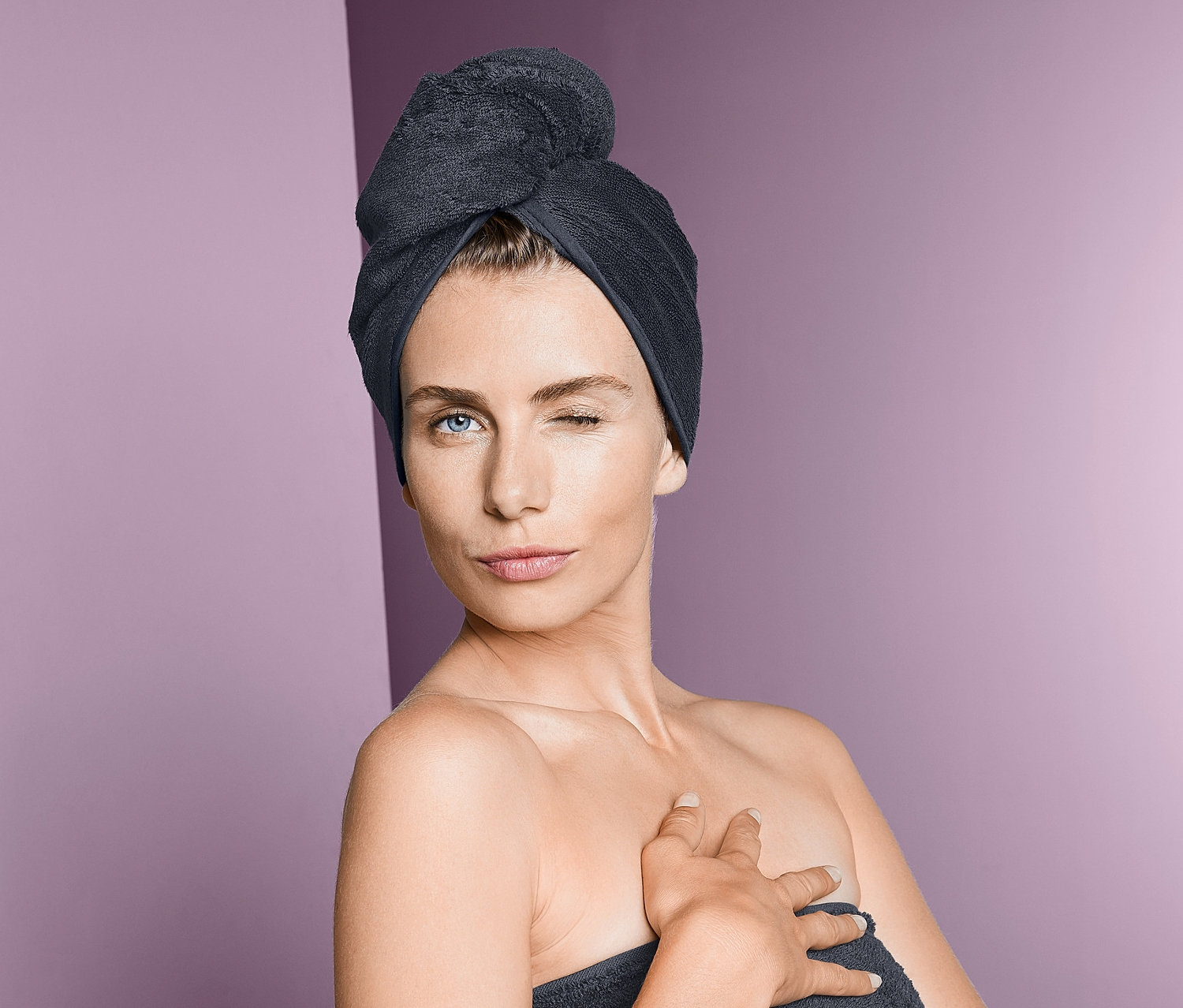 Žena mrká a nosí ručníkový turban a ručník.