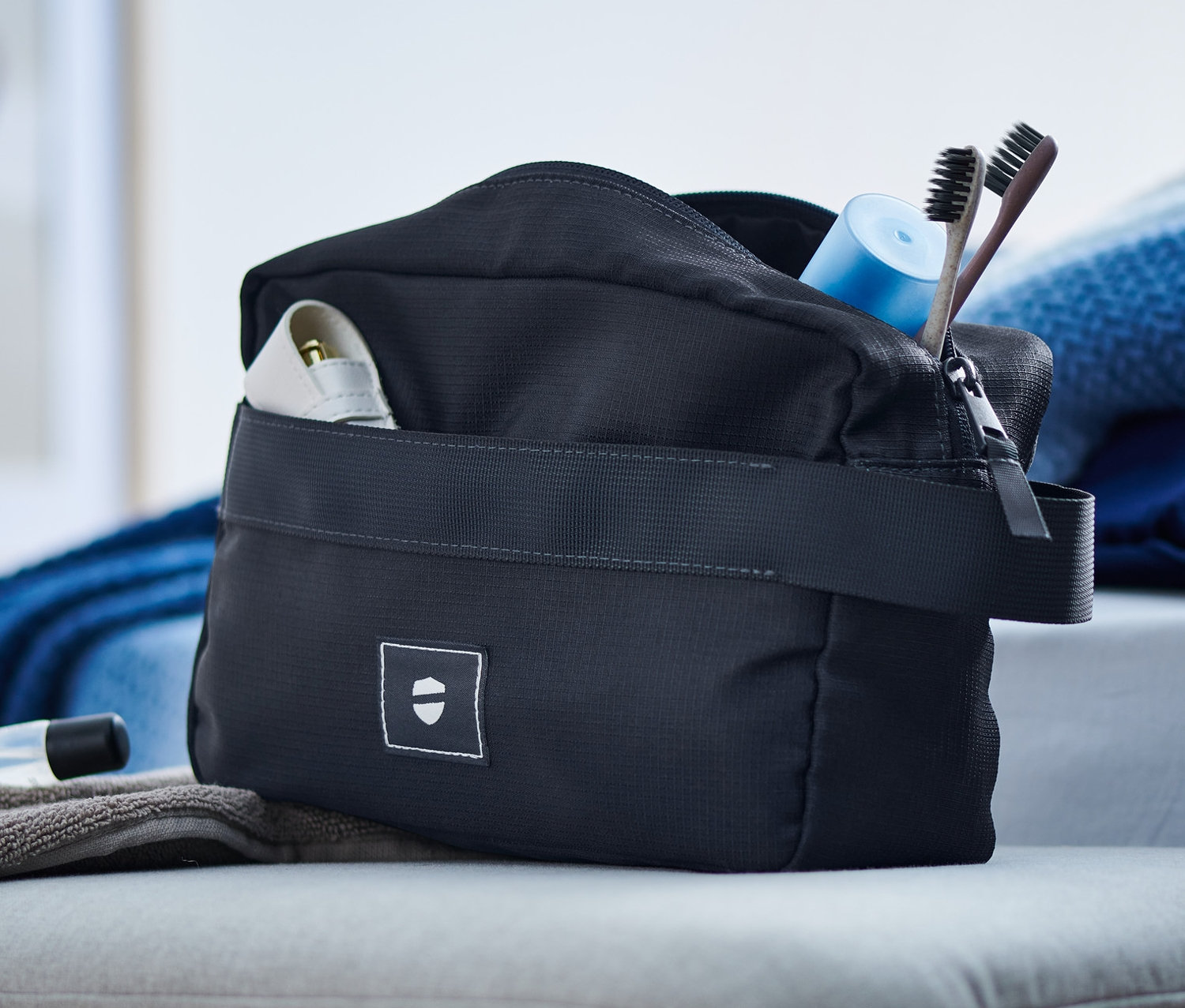 Na taburetu leží toaletní taštička, ručník a kosmetika.