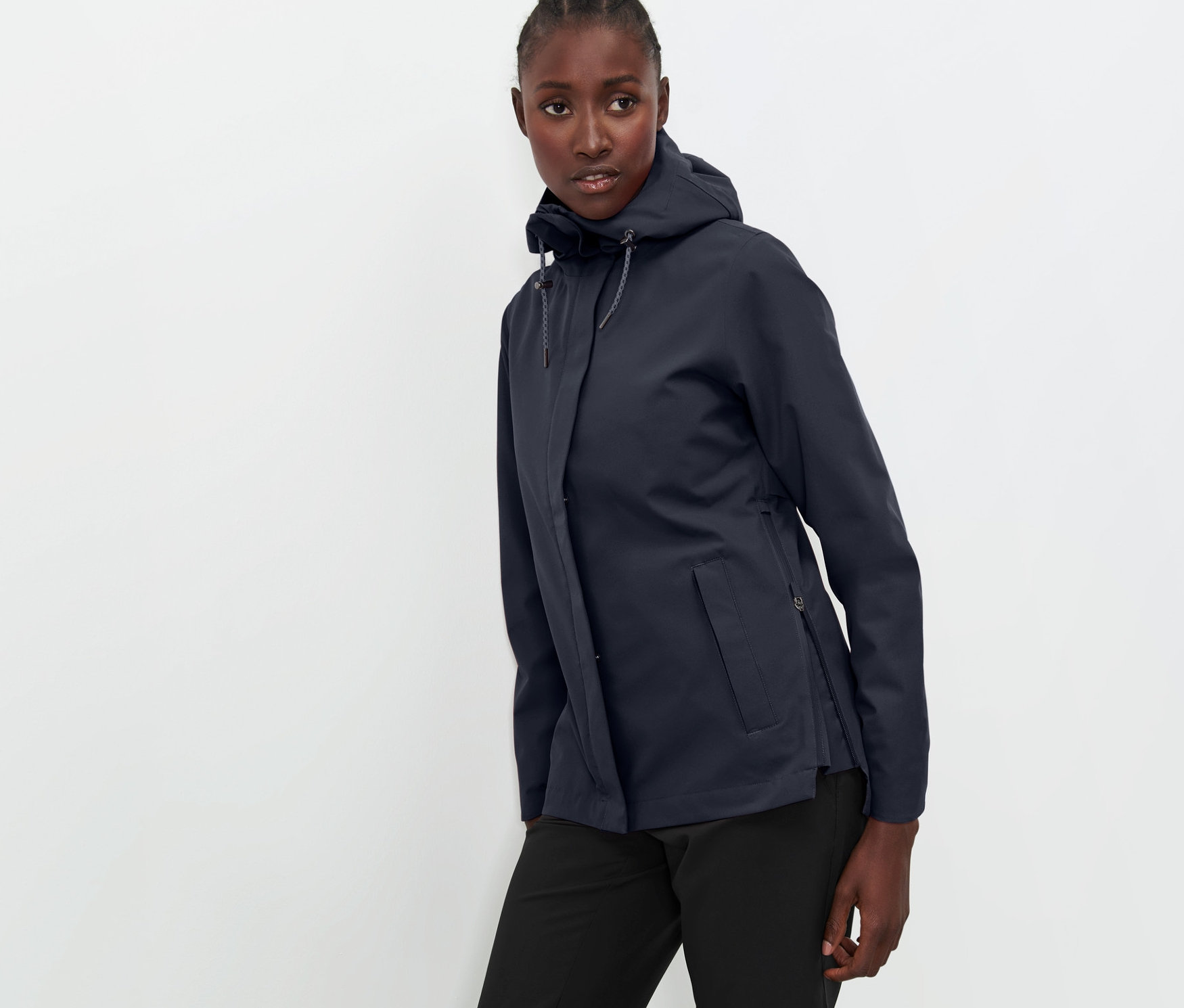 Žena pózuje v tmavě modré funkční outdoorové bundě a černých kalhotách.