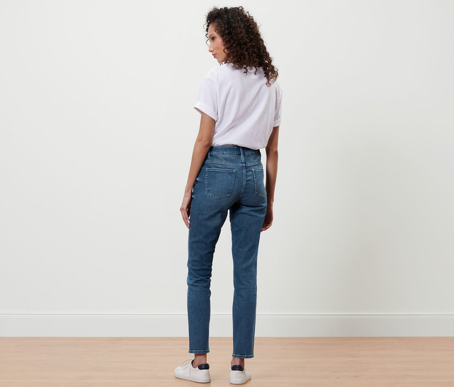 Žena stojí zády k fotoaparátu a má na sobě džíny Slim »Fit Emma«, středně modrý denim, bílé tričko a tenisky.