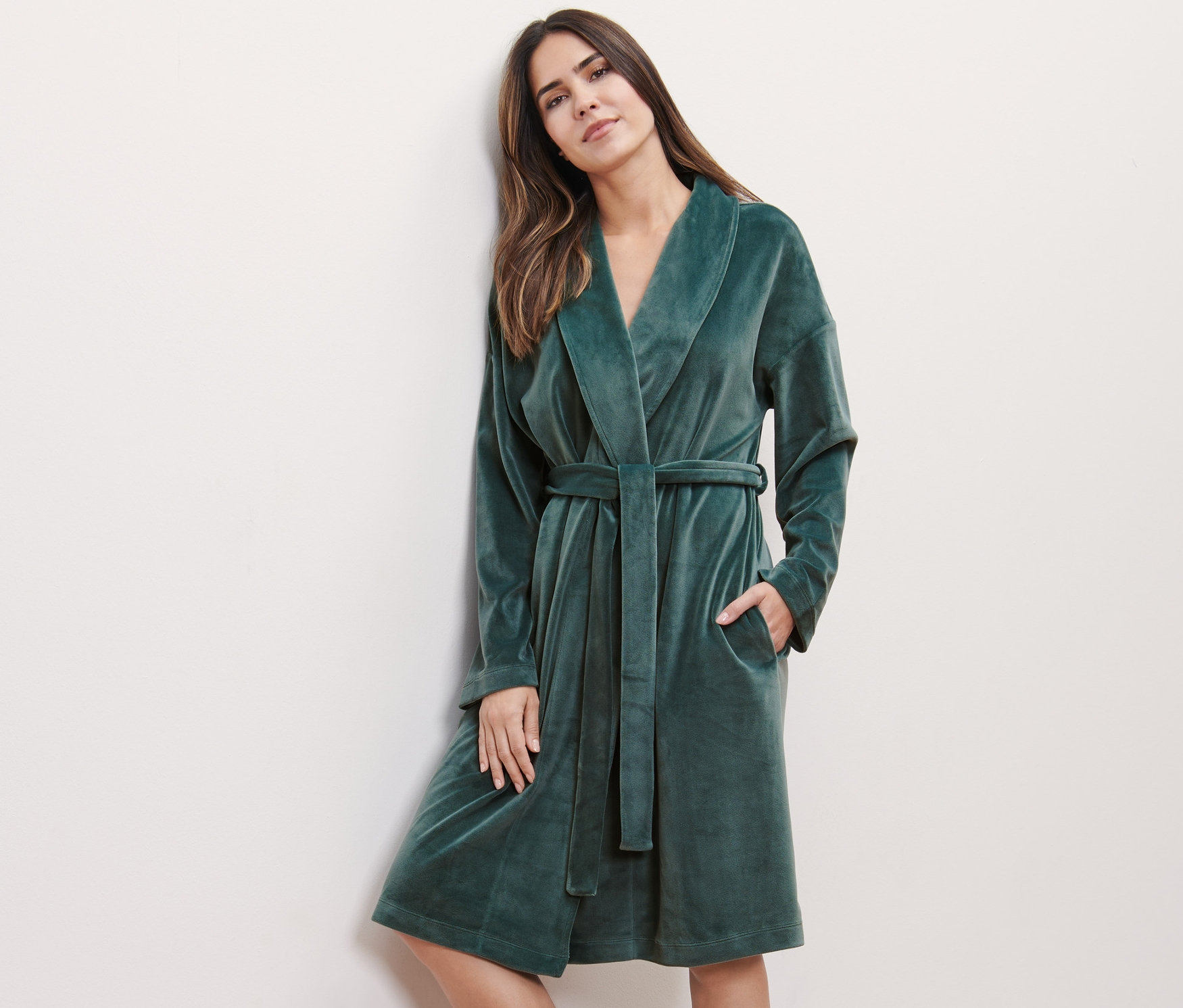 Žena opřená o stěnu má na sobě plyšový župan.