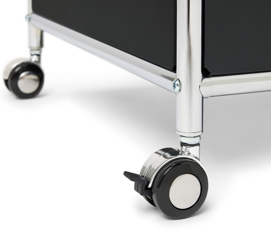 Detail kovové komody »CN3« s jednou zásuvkou, výklopnými dvířky a obvodovou ohrádkou, stojící na kolečkách.