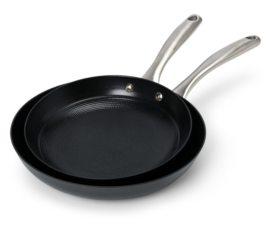 Dvě černé pánve s ocelovými rukojeťmi leží na sobě.