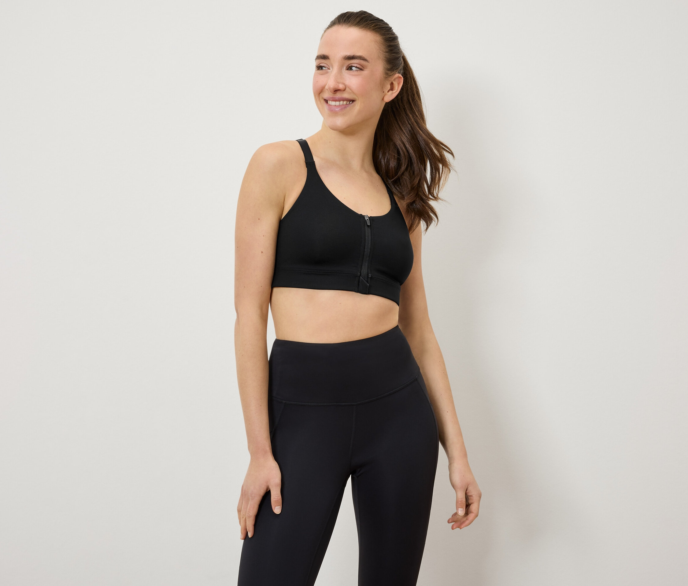 Žena má na sobě černou sportovní podprsenku a legíny.