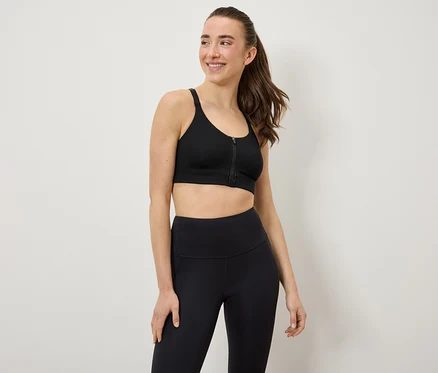 Žena má na sobě černou sportovní podprsenku a legíny.