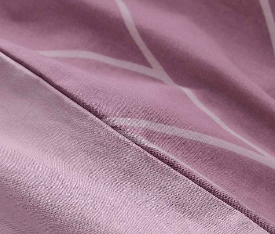 Detail fialového povlečení s bílými geometrickými vzory.