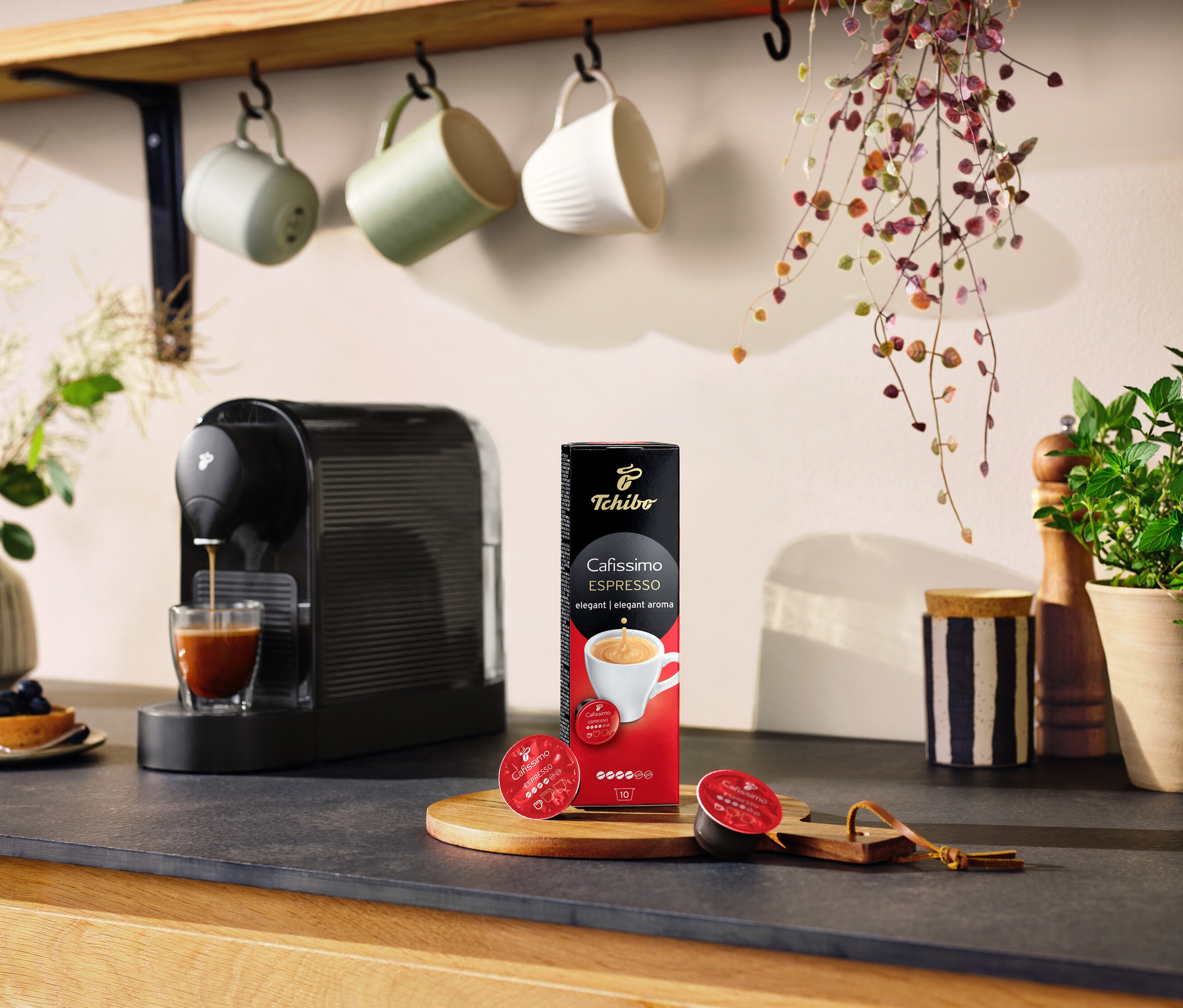 Espresso stroj nalévá kávu do sklenice vedle balení Cafissimo Espresso elegantní 10 kapslí.