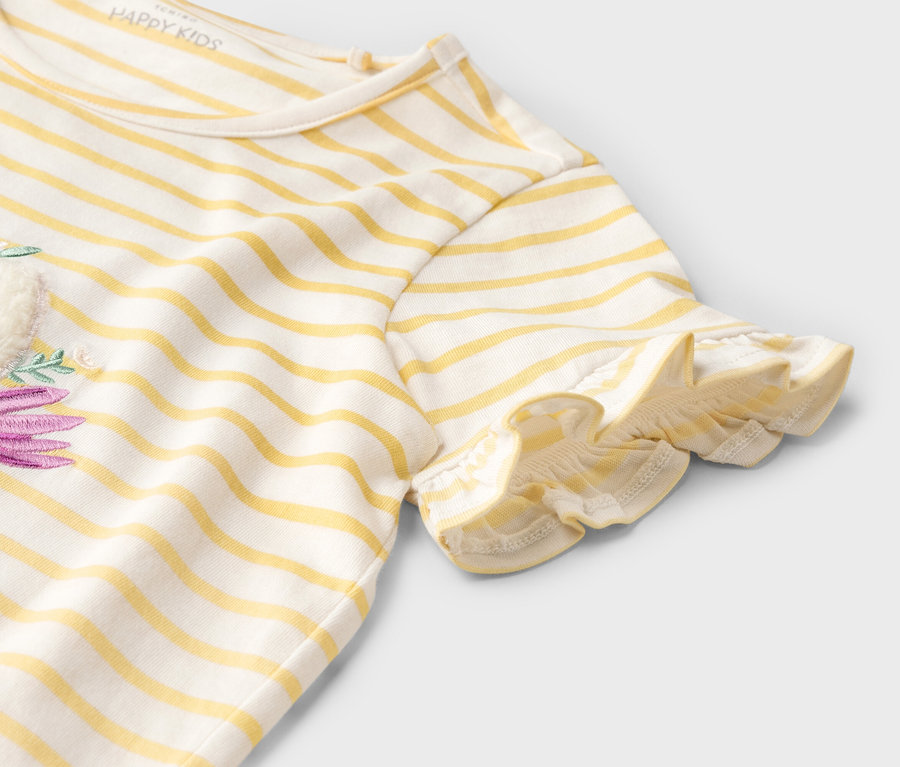 Detail žluto-bílého pruhovaného trička s krátkým rukávem a fialovým květinovým vzorem.