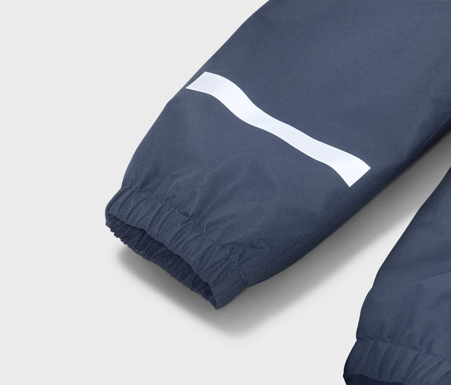 Detailní pohled na modrý rukáv bundy s bílým vlnitým pruhem a elastickou manžetou.