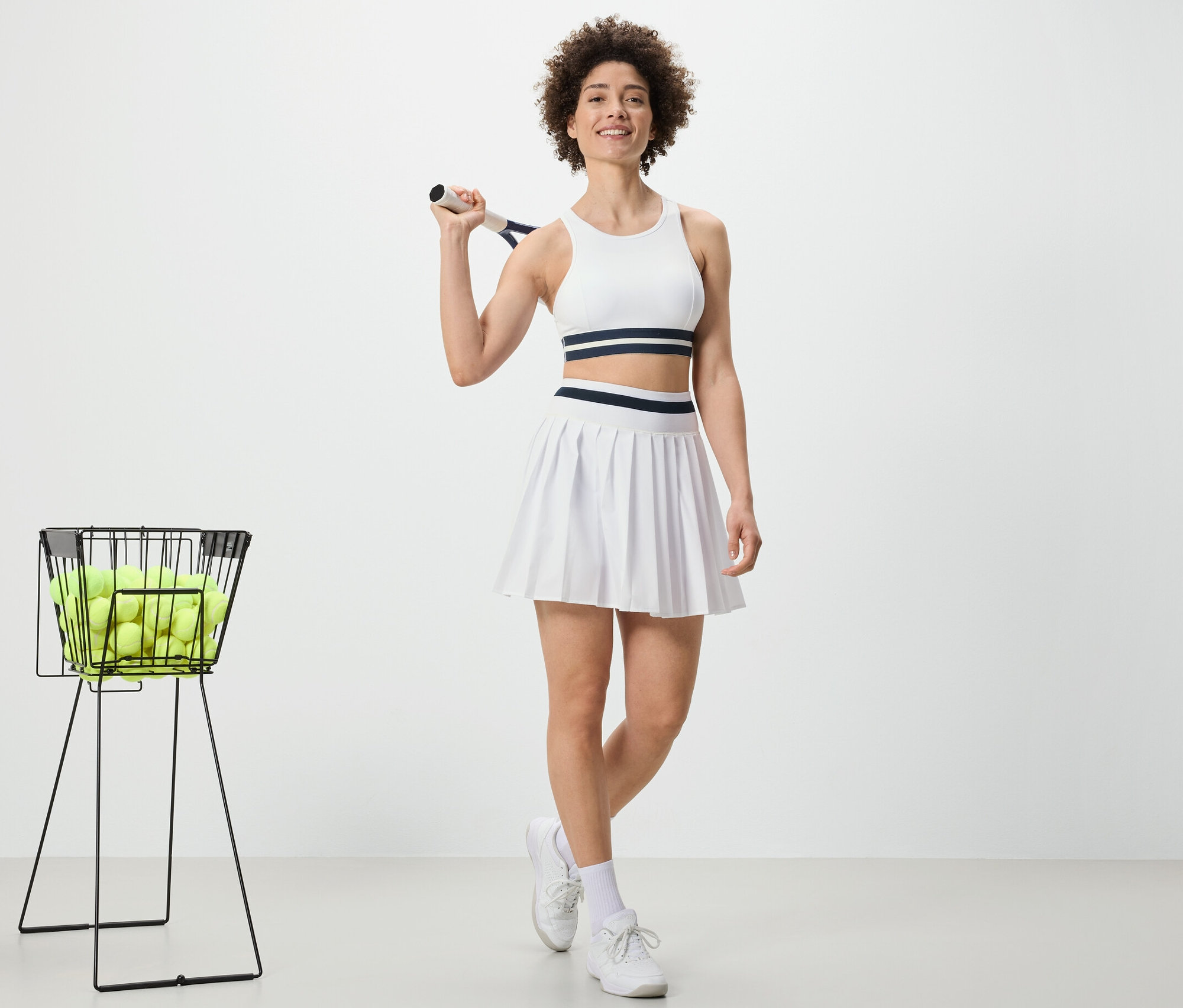 Žena drží tenisovou raketu a má na sobě sportovní sukni.