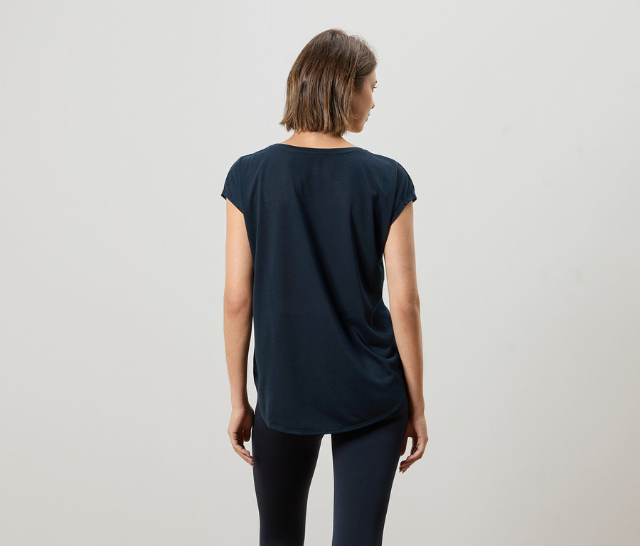 Pohled zezadu na ženu s krátkými hnědými vlasy v tmavě modrém tričku a legínách.