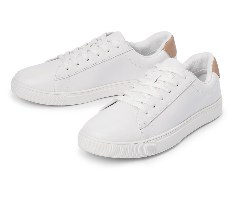 Dvě bílé tenisky se šňůrkami a světle hnědým detailem na patě leží vedle sebe.