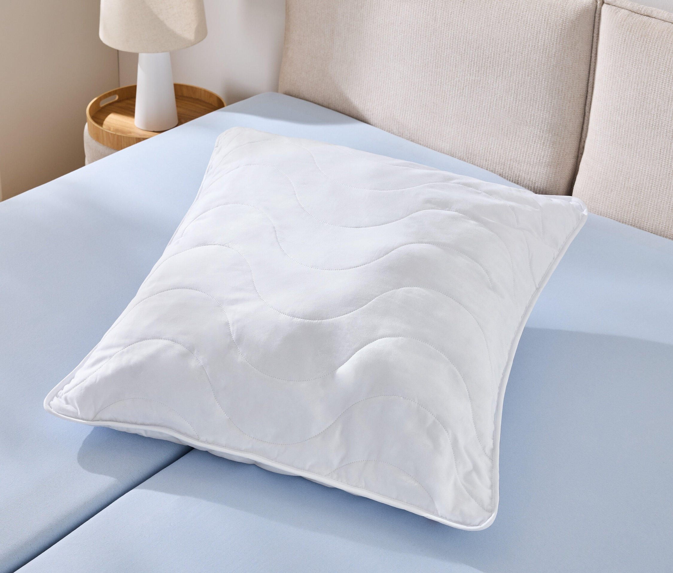 Jeden bílý polštář odolný proti varu (cca 90 x 70) leží na světle modrém prostěradle.