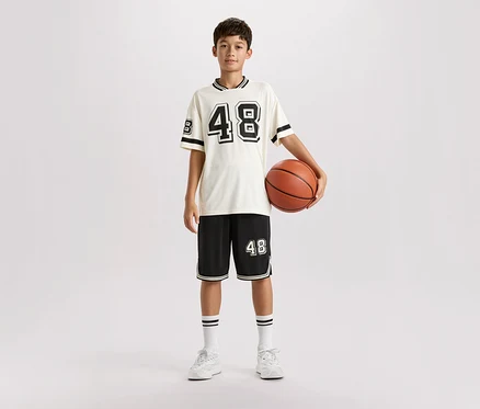 Mladý muž stojí ve sportovním oblečení a drží basketbalový míč.