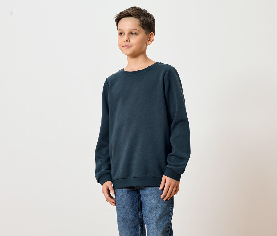 Mladý muž má na sobě tmavě modrou mikinu a džíny.