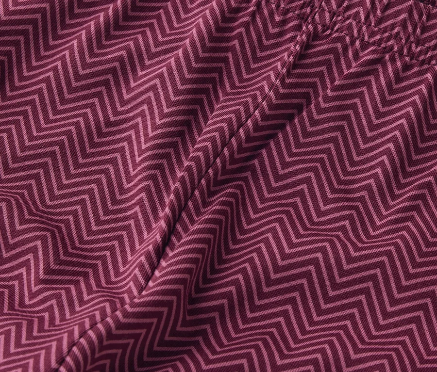 Detailní záběr na vínově červené látkové šortky s cikcakovým vzorem.