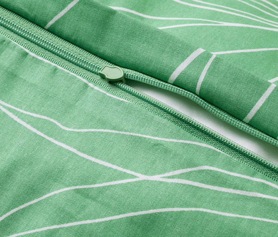 Detailní záběr na zelený povlak na přikrývku s bílým květinovým vzorem a zipem.