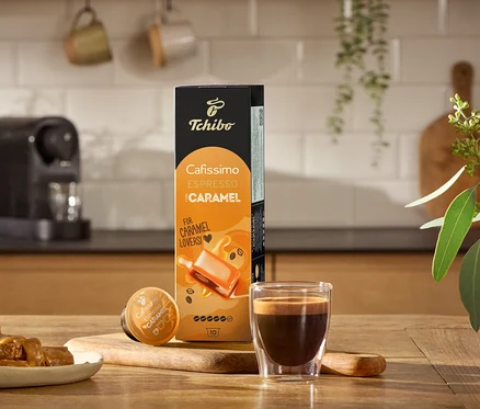 Espresso, karamelky a balení Cafissimo Flavoured Edition: Espresso Caramel – 80 kapslí na dřevěném stole.