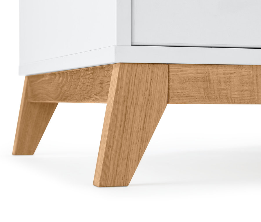 Detail spodní části bílé šatní skříně s dřevěnýma nohama.