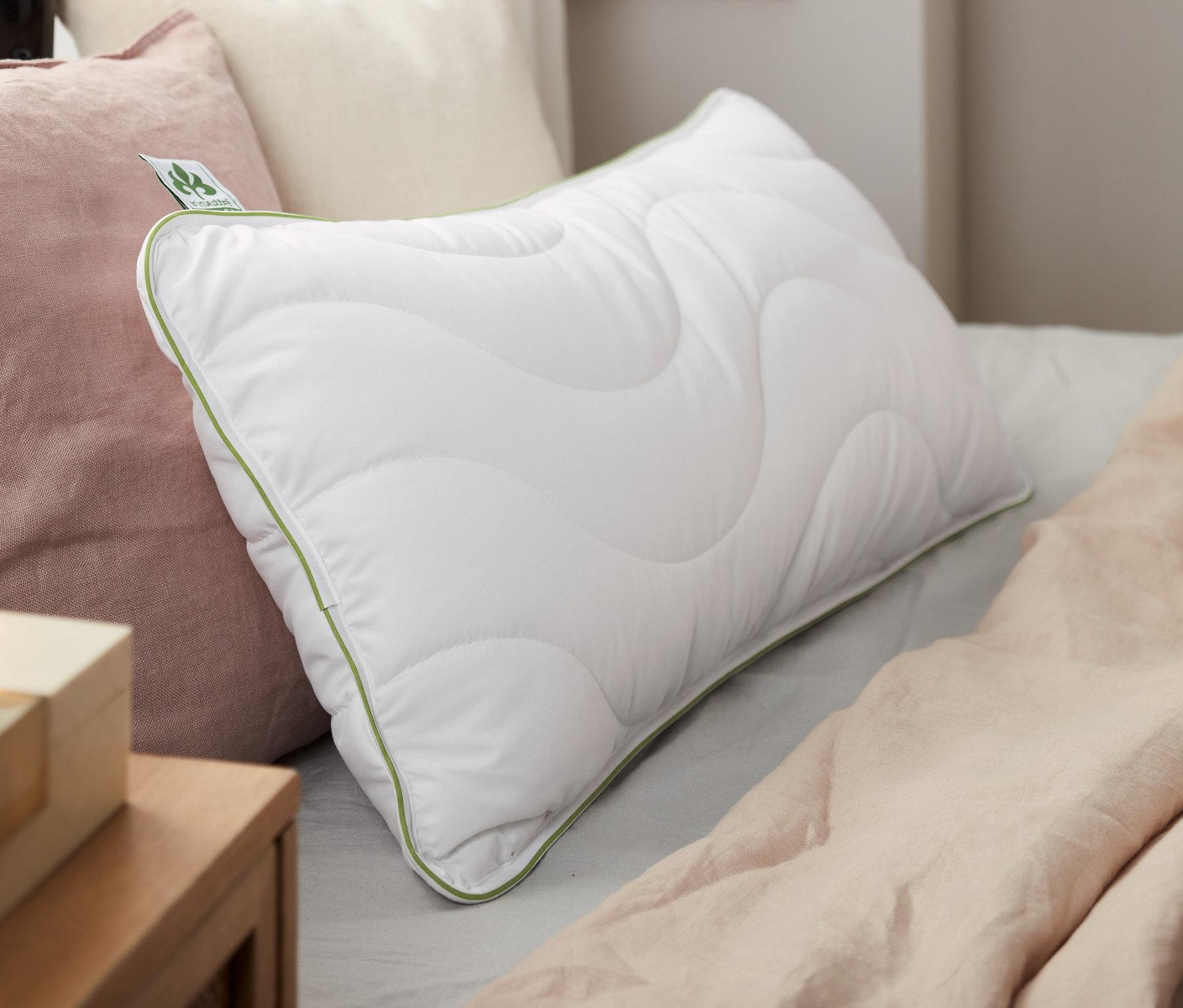 Na posteli leží dva bílé polštáře irisette® greenline o rozměrech cca 80 x 40 cm.