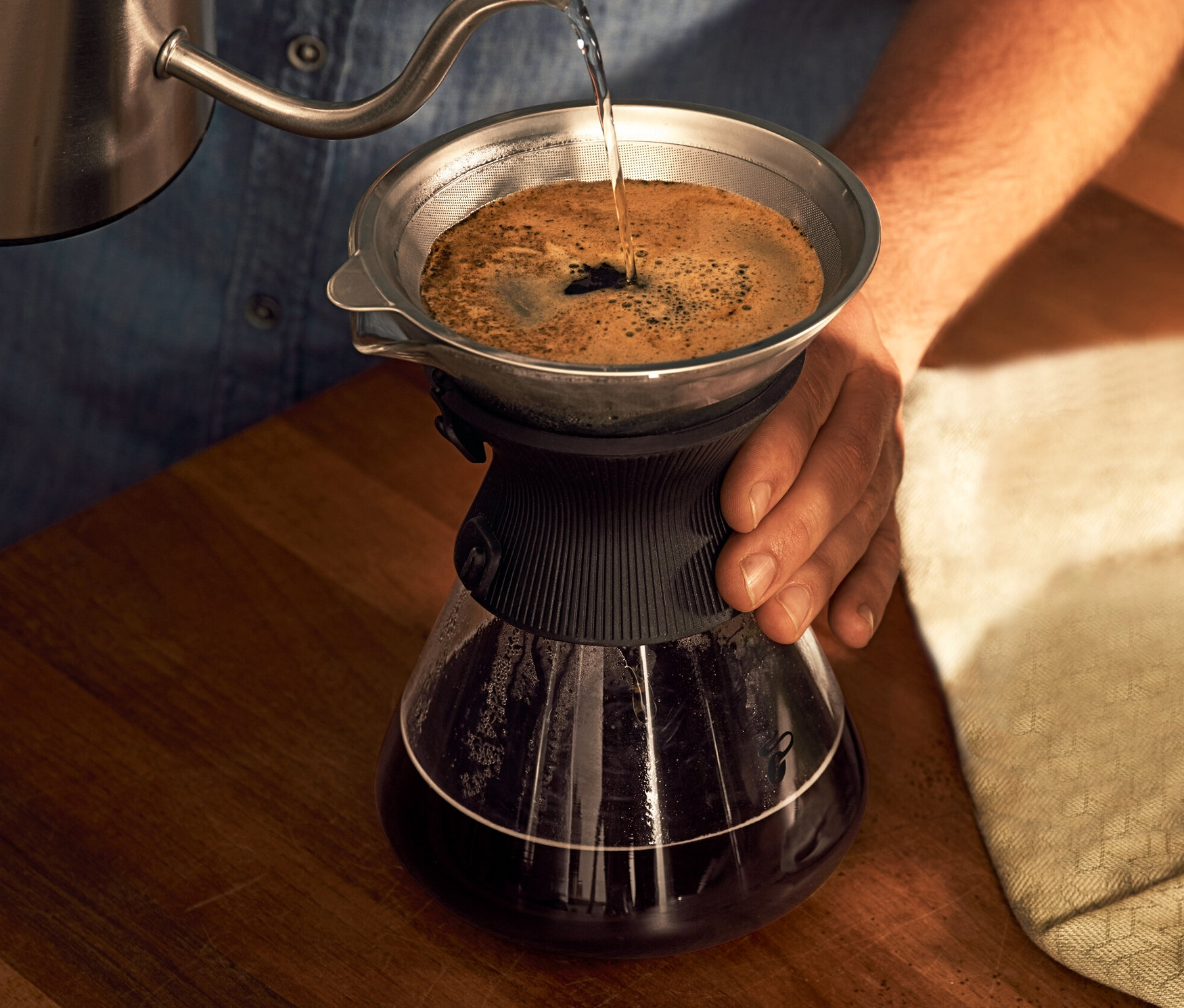 Muž nalévá vodu do skleněné karafy BEEM Pour Over 0,75 l s filtrem na kávu.