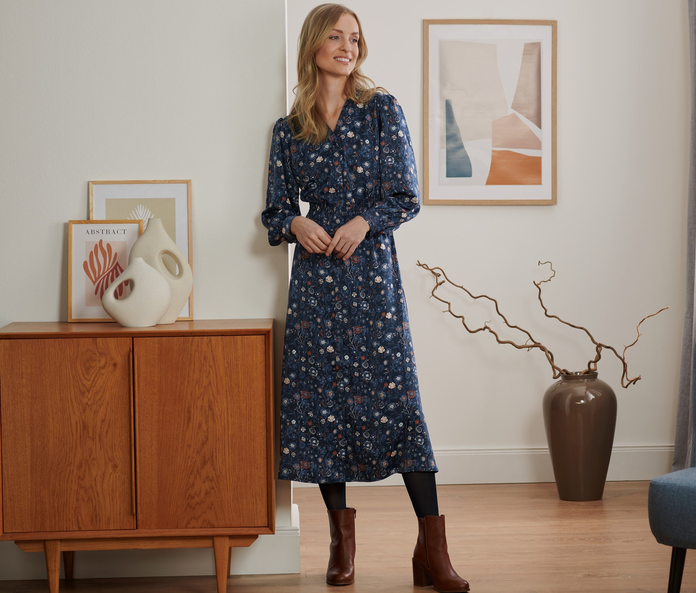 Žena stojí v místnosti a má na sobě květované šaty.