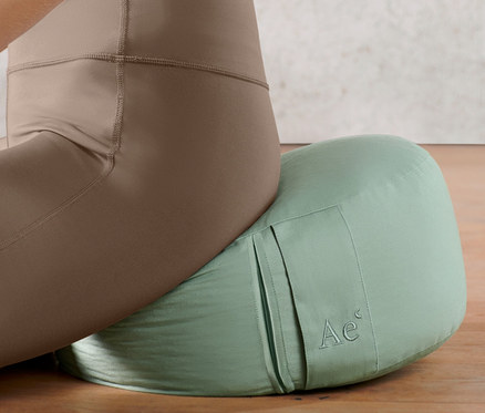 Žena sedí na meditačním polštářku.