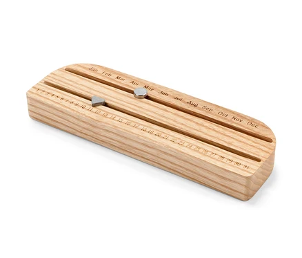 Dřevěný věčný kalendář s posuvnými magnety ukazujícími den a měsíc.