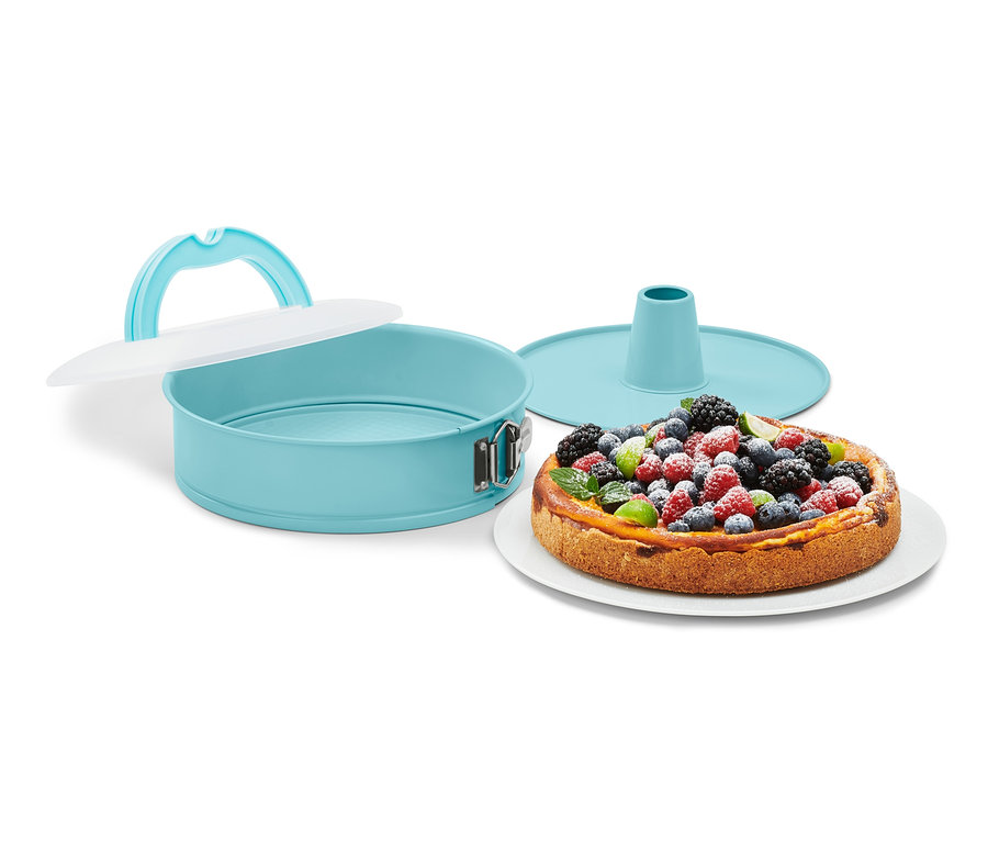 Tyrkysová forma na dort s přepravním víkem vedle dortu s ovocem.