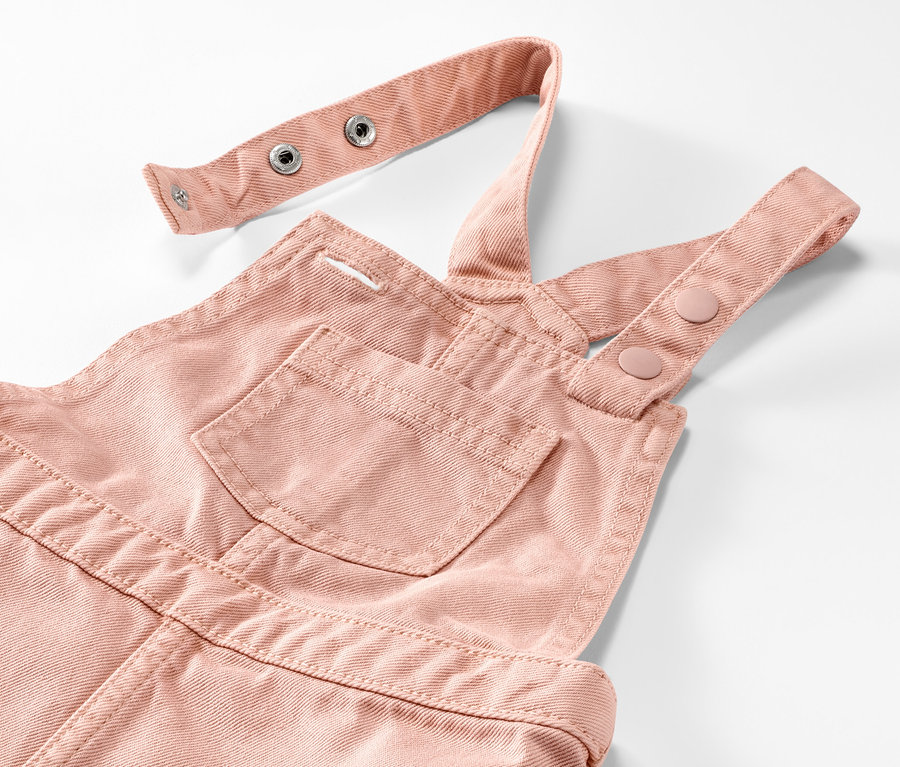 Detail dívčích šatů s laclem v růžové barvě.