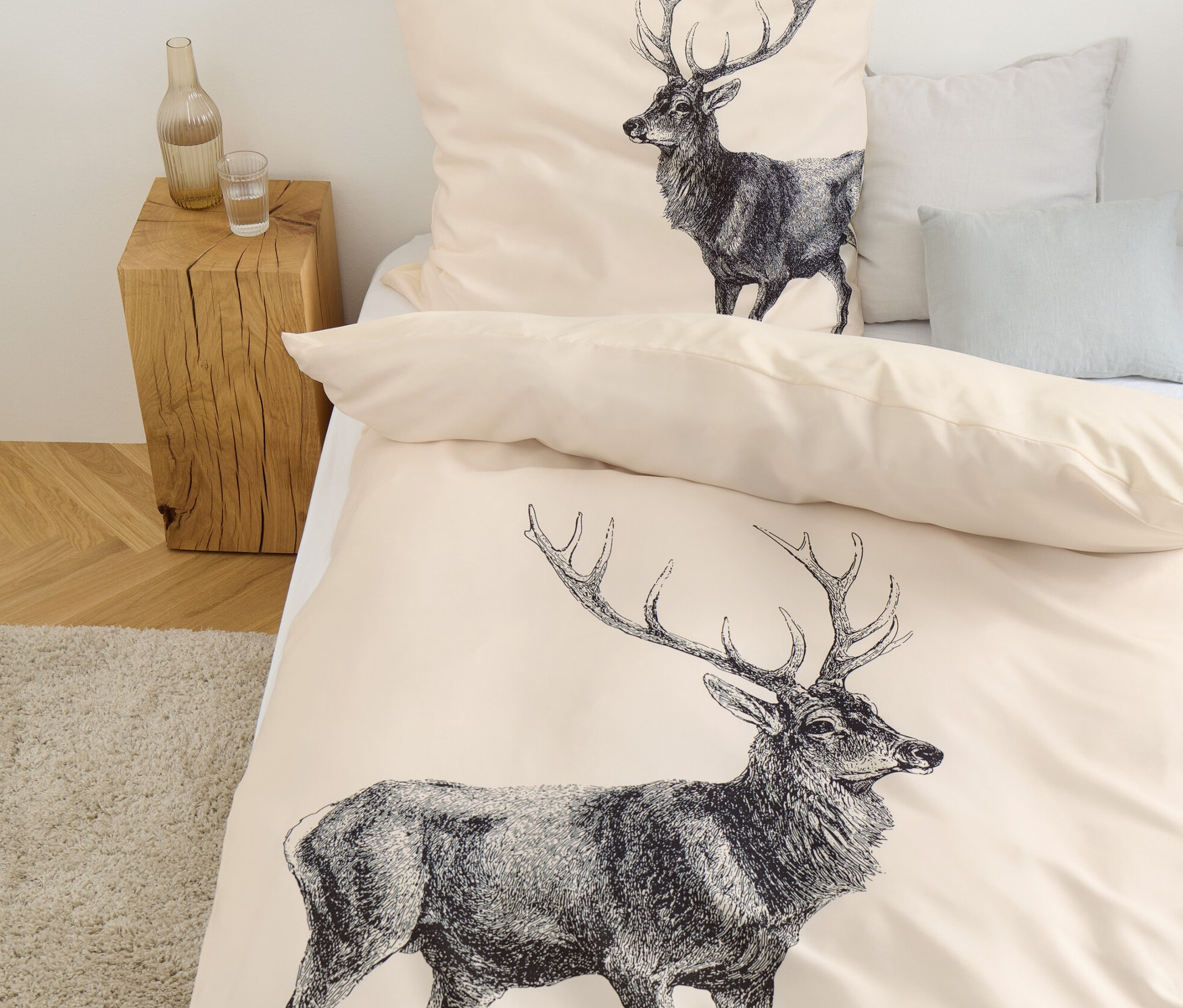 Béžové povlečení s potiskem jelena leží na posteli.