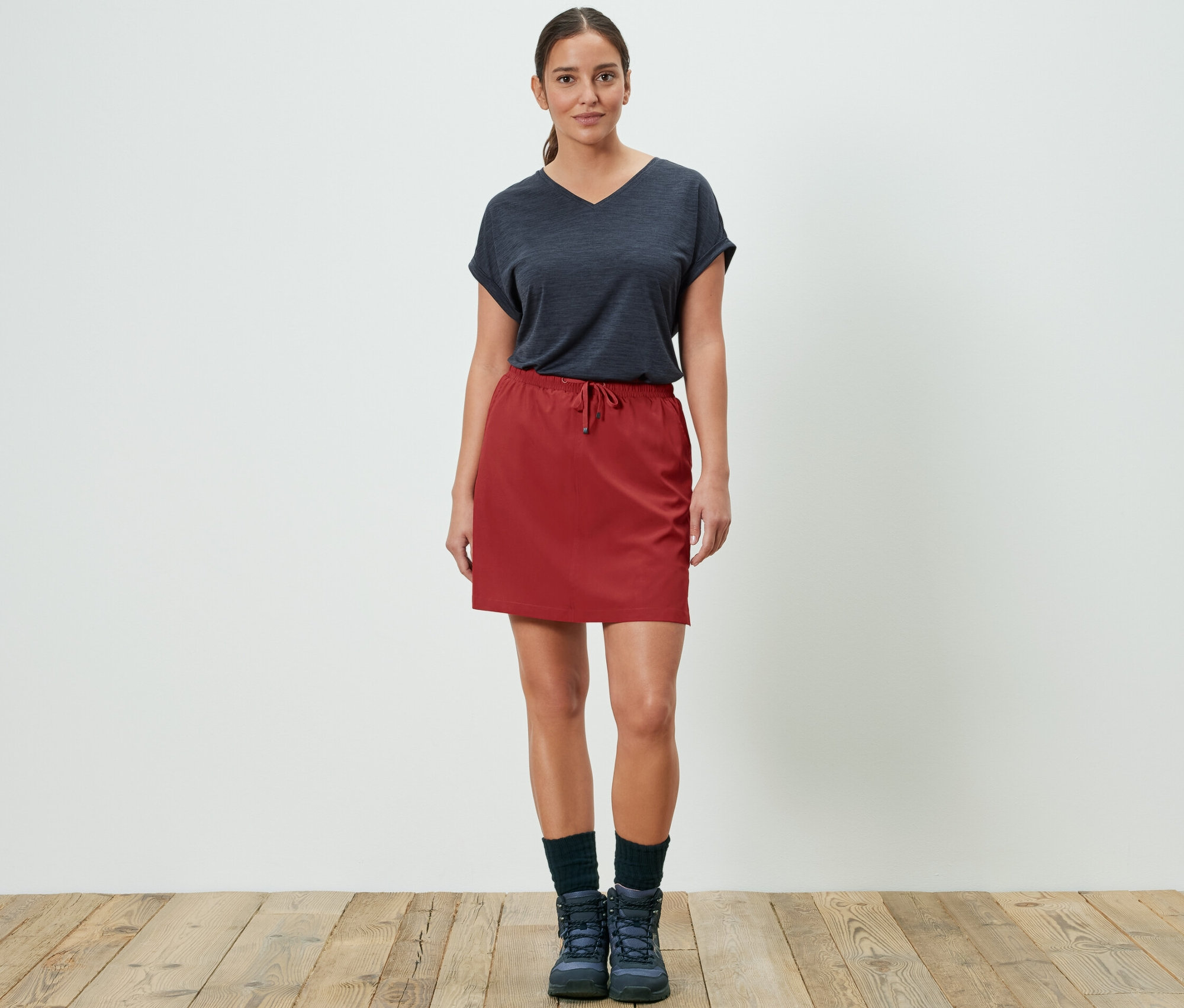 Žena pózuje v červené funkční kraťasové sukni.