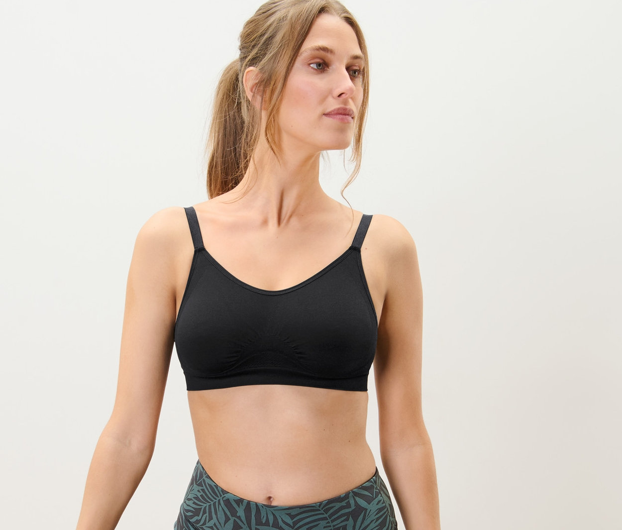 Žena stojí v pozici stromu a má na sobě bezešvou sportovní podprsenku.