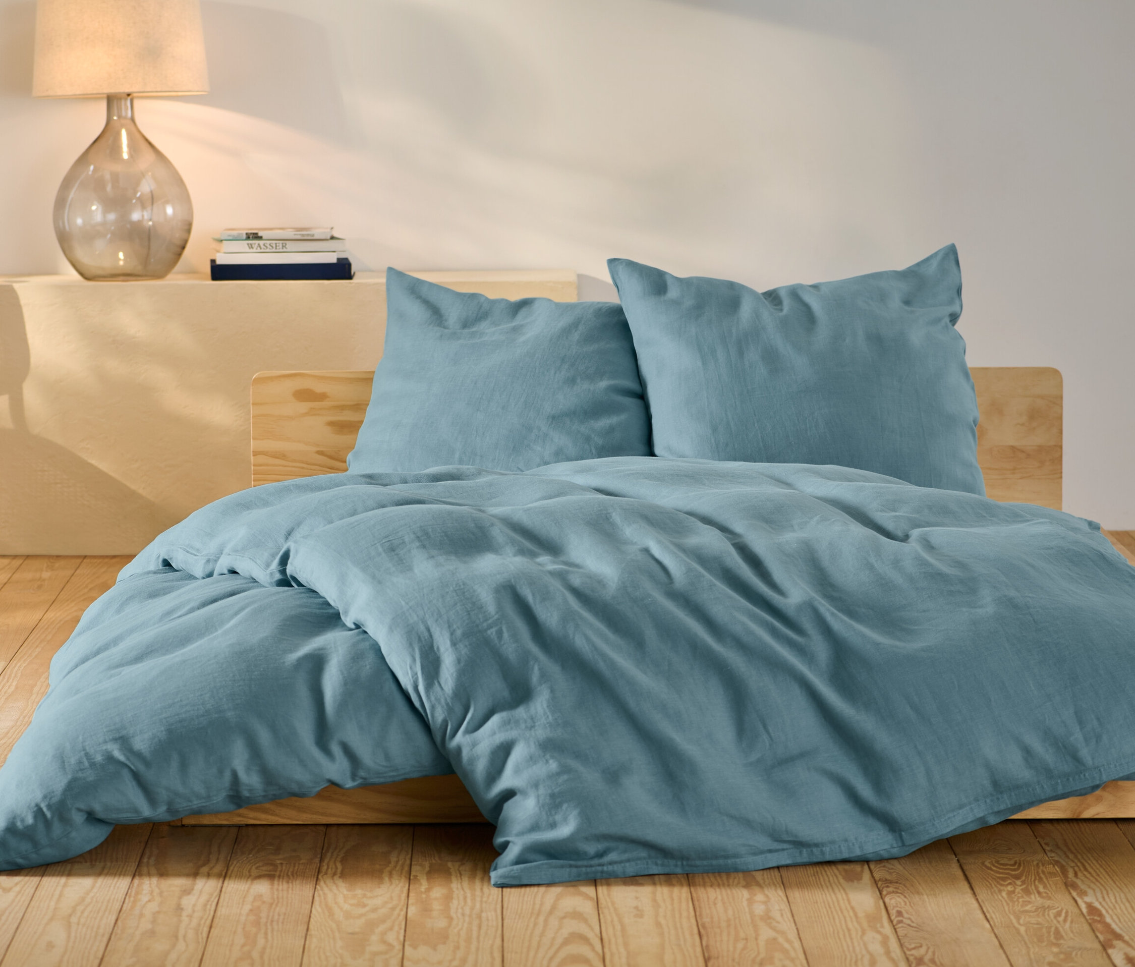 Modré lněné povlečení standardní a nadměrné velikosti na posteli.