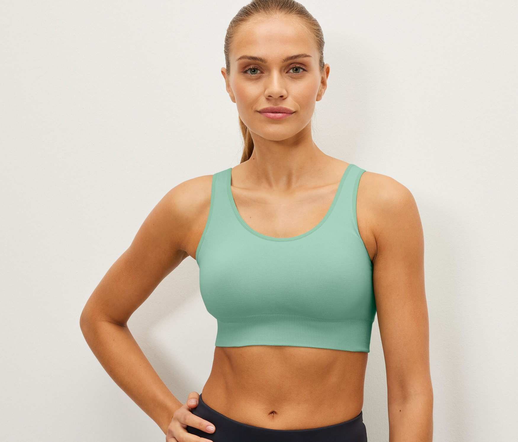 Žena pózuje v mátové bezešvé sportovní podprsence.