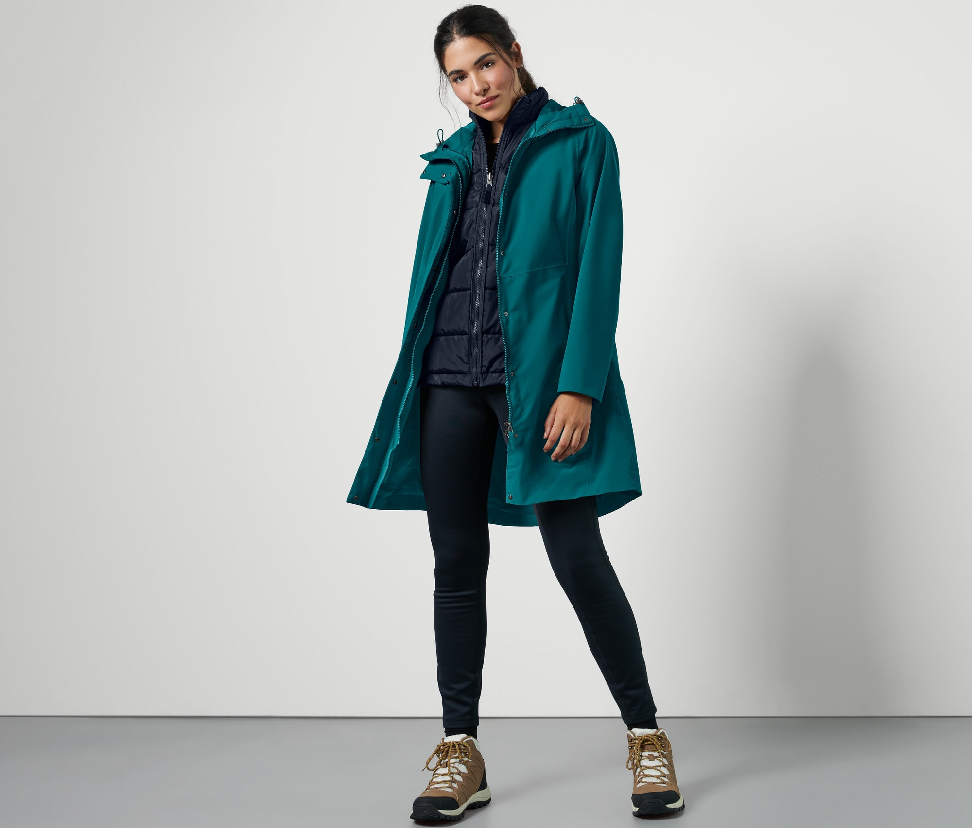 Žena pózuje v outdoorovém kabátu s vestou 3 v 1, petrolejové barvy.
