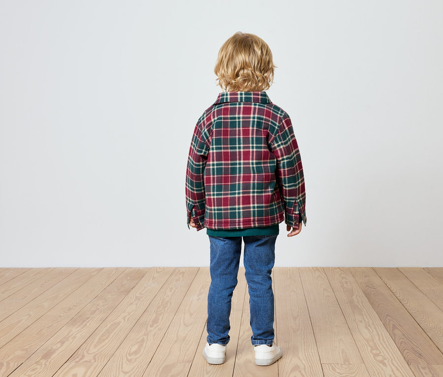 Chlapec stojí zády, má na sobě kostkovanou košili, džíny a tenisky.