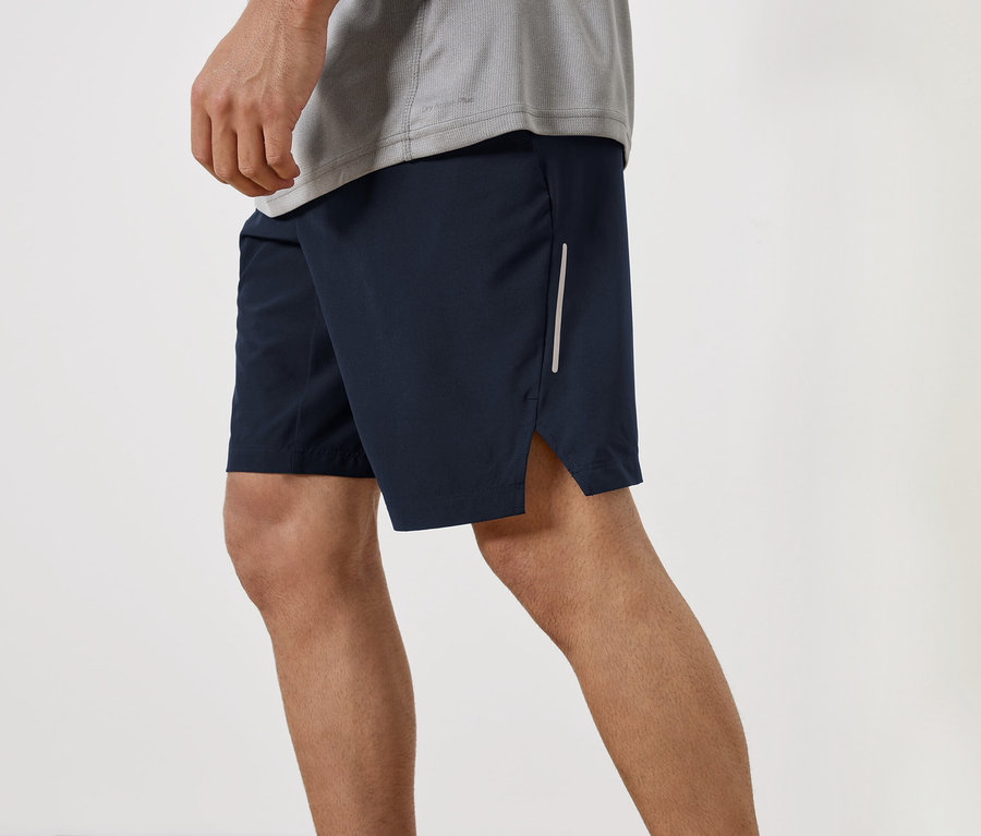 Muž má na sobě tmavě modré šortky a šedé tričko.