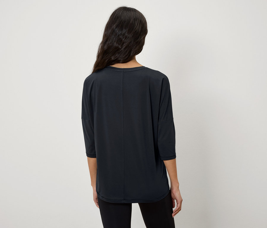 Žena zády k fotoaparátu má na sobě černé tričko s tříčtvrtečními rukávy.