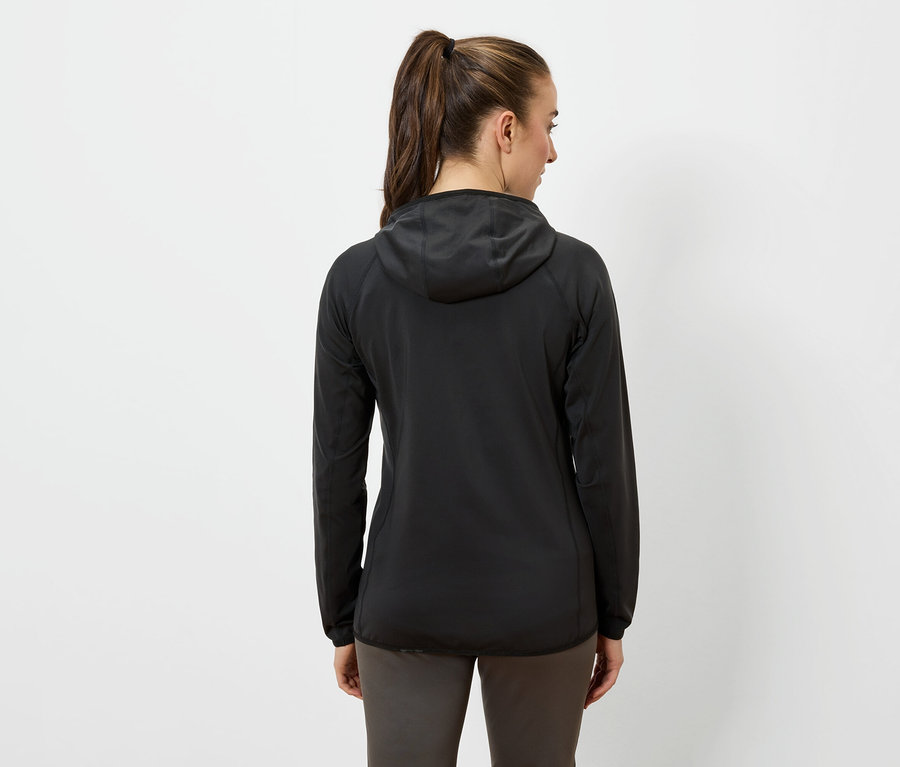 Žena zády k fotoaparátu má na sobě černou bundu s kapucí a tmavé kalhoty.