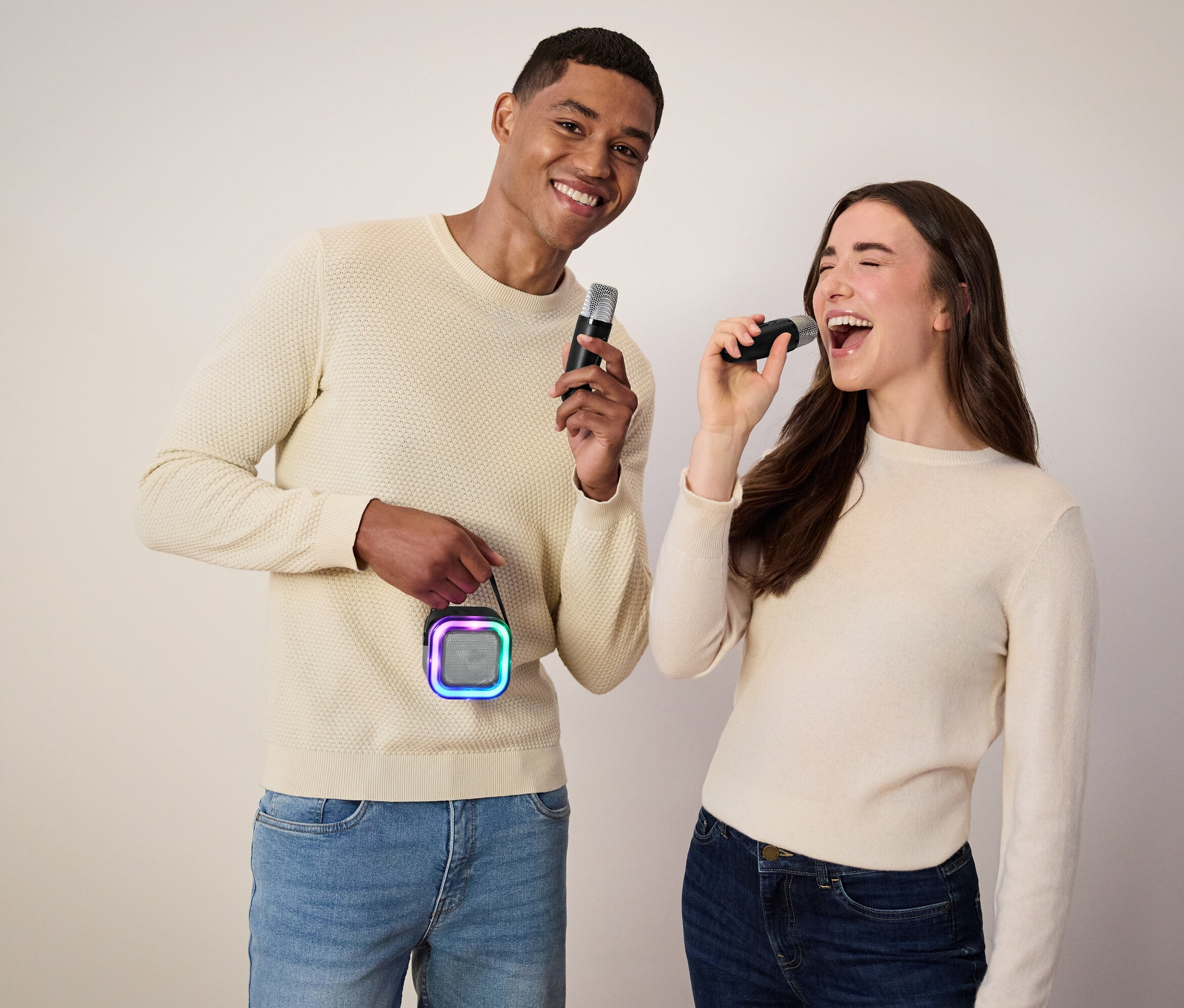 Muž drží mikrofon a reproduktor, žena zpívá do mikrofonu.