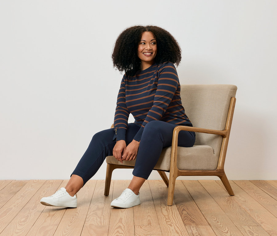 Žena sedí v křesle a má na sobě joggpant.